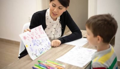 Five years old boy drawing at the psychotherapy session.