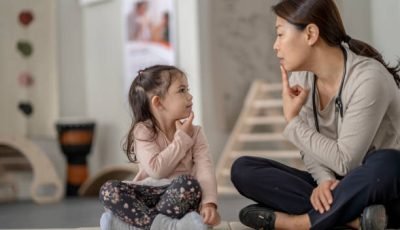 A therapist guides a young girl through speech therapy exercises using a playful and modern approach.